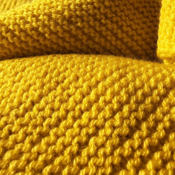 Detailaufnahme handgestrickter gelber oversize Schal. Trym