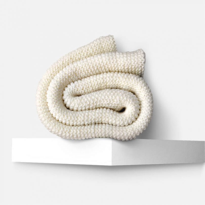 Produktfoto weißer handgestrickter oversize Schal auf Regal. haldor