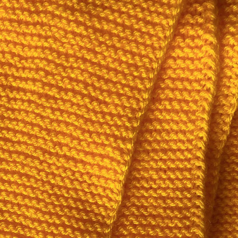 Detailaufnahme handgestrickter gelber oversize Schal für Kinder. Eeli